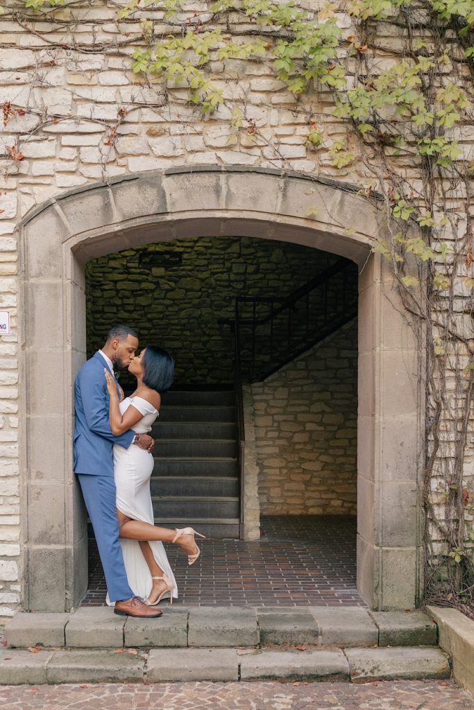 Bride and groom sharing a kiss under a beautiful arch during their dallas texas wedding