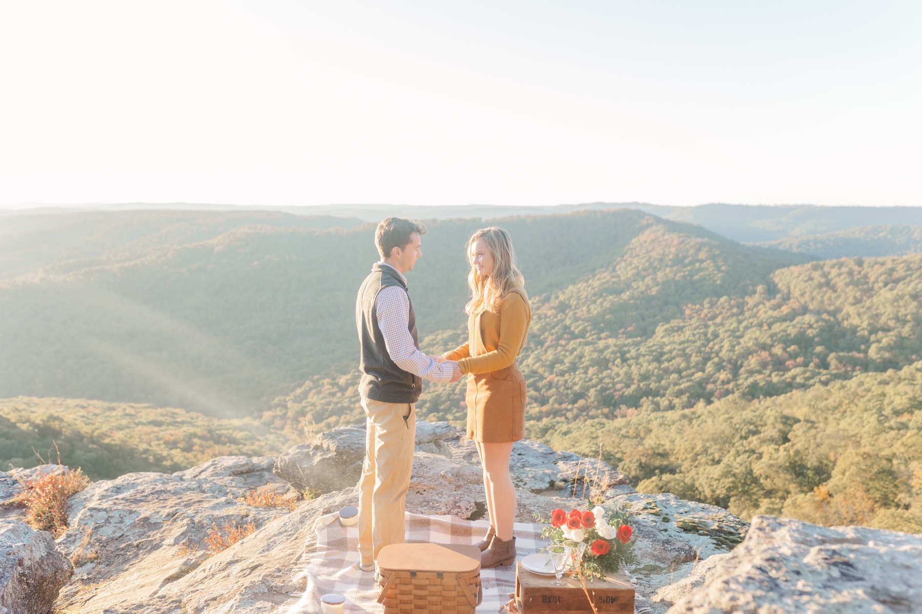 man and woman holding hands facing each other during their white rock mountain arkansas surprise proposal