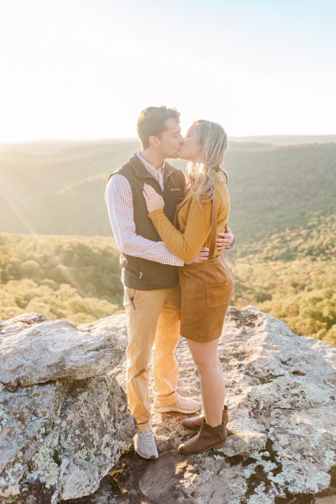 woman and man sharing a kiss at white rock mountain arkansas during their surprise proposal